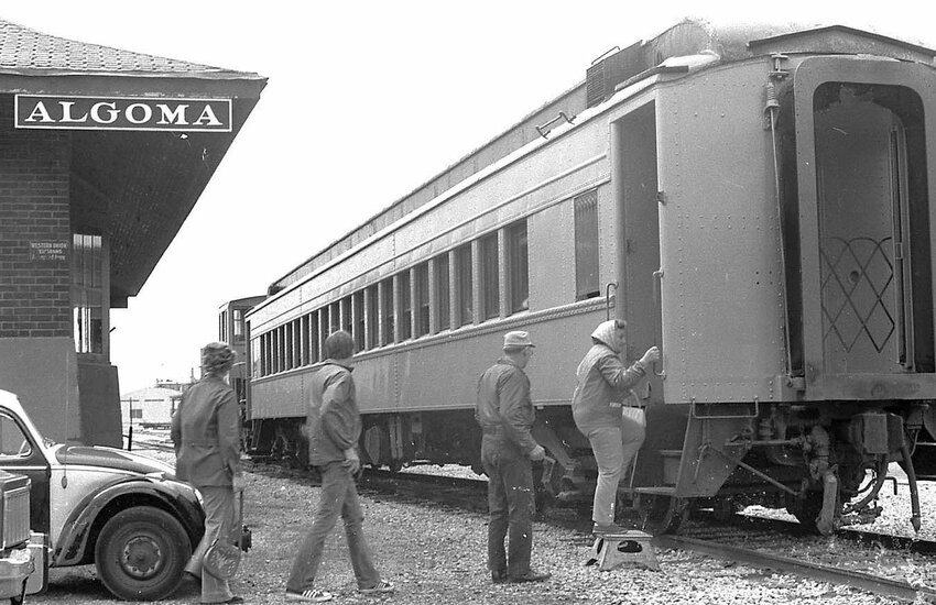 Harold Heidmann shot this photo in 1976 as passengers were boarding an excursion train at the Algoma depot, bound for Casco. Passengers that day were looking for a unique experience on the Ahnapee & Western tracks.</p><p>One experience they did not have that day was drinking from public-use cups. By early fall of 1910, the State of Wisconsin mandated the end of public cups on trains, and passengers who didn’t bring their own cups were compelled to buy one if they wanted a drink. Patrons were not happy so, as an accommodation, informative placards were hung above drinking places in trains and stations. Strange as it would have seemed to the 1976 passengers, public cups were preferred in 1910.</p><p>Heidmann’s photos are found at Algoma Public Library.