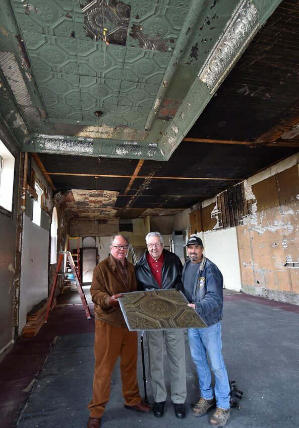 Art Schiller, from left, Maynard Lufter and Tom Skubal show a tin ceiling tile in which 100-year-old Lufter's father Frank installed in the 1920s inside the former Selner Plumbing & Heating building in Kewaunee. The three-story building, now owned by Schiller, is being renovated with the help of historian Skubal.