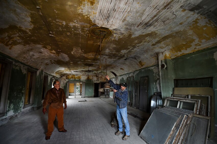 Tom Skubal, right, displays one of the gas chandeliers that lit Grimmer's Hall, a ballroom that occupied the top floor of the former Selner Plumbing & Heating building in Kewaunee. Skubal is working to gut the building for renovations by the building's new owner, Art Schiller, left.
