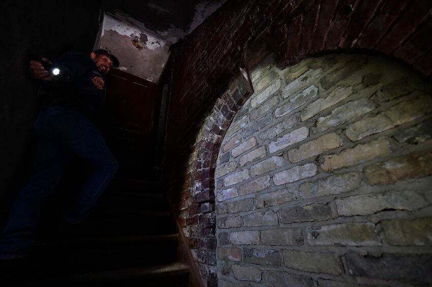 Tom Skubal shines a light on an arched back entrance that was walled over in the former Selner Plumbing & Heating building that Selner is helping to renovate.