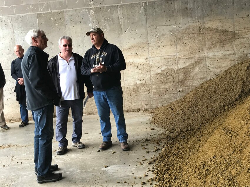 Gov. Tony Evers, foreground, talks with Deer Run Dairy operators Duane Ducat, middle, and Dale Bogart on Tuesday, May 28, about the farm's manure digester. The remains of the cleaned-up waste after processing are on the right.
