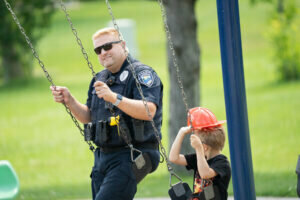 Officer Brian Arkens took a turn on the swings at Patriot Park with a PACK attendee. Andrew Pantzlaff photo