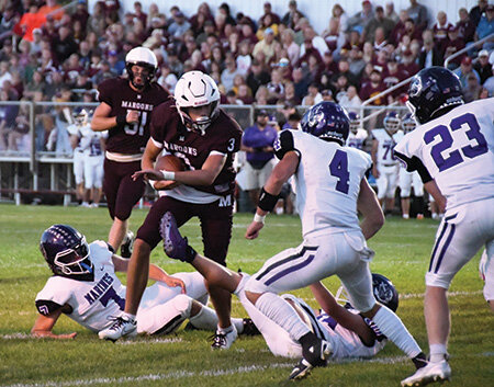 Menominee’s Tanner Theuerkauf slips through a couple Marine tackles as Marine Chase MacGregor squares up on him.