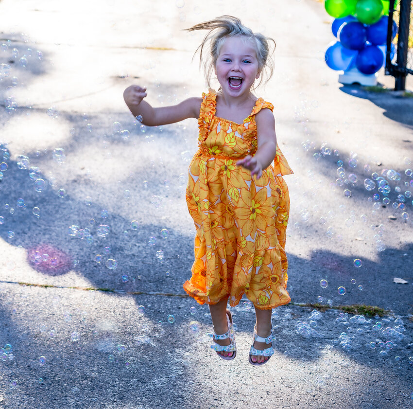 Wren Abegglen jumps for joy in the bubbles at the entrance to the Encompass Big Event for Kids.