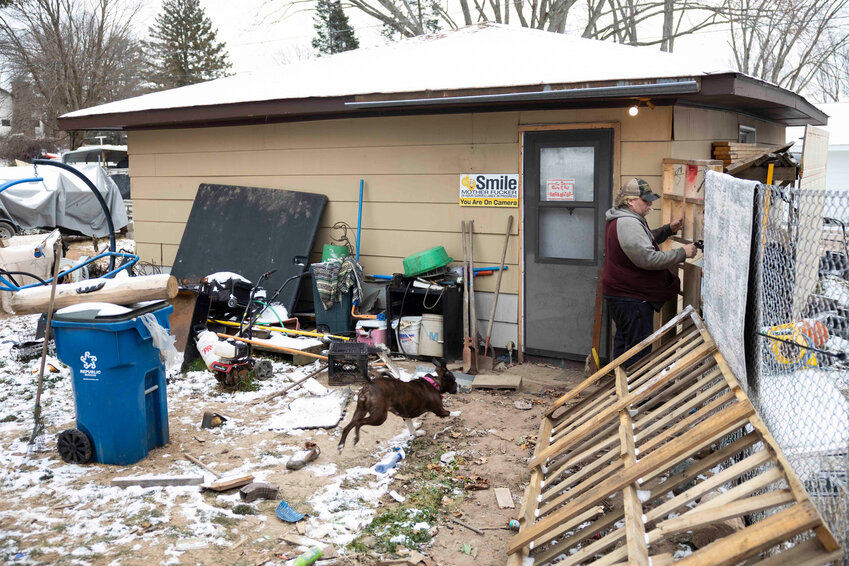 Eric Zieroth unlocks the back gate of the apartment where he’s staying as his dog, Bella, runs after him before driving to his storage unit with his daughter, Christina Hubbell, on Dec. 3. Joe Timmerman / Wisconsin Watch photo