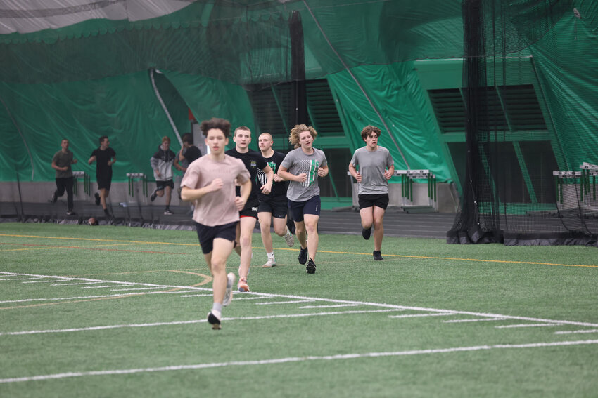 A group of track athletes runs back on to the turf after completing a warmup lap around the outside of the Hodag Dome.
