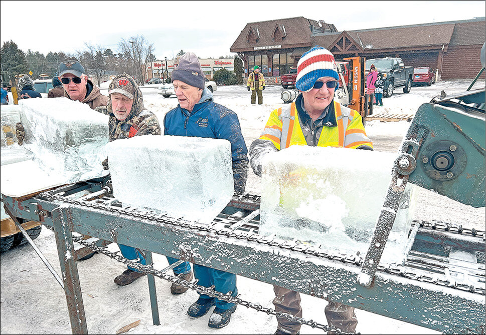 Former Eagle River Fire Department Fire Chief Pat Weber (right) and volunteers guided 13-inch blocks of crystal clear ice through a shaver to make them a uniform size prior to construction of the Eagle River Ice Castle near the railroad depot.