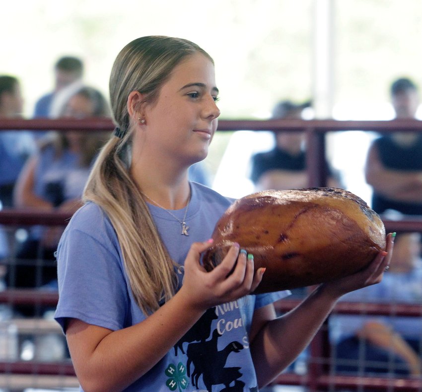 In this July 2021 file photo, Karlie McGee holds up the smoked ham she entered in the 2021 Randolph County 4-H/FFA Fair Blue Ribbon Auction held July 16 at the Riley Pavilion in Moberly's Rothwell Park. The 2022 fair opens this weekend with tractor pulls Friday and Saturday nights. Exhibits and shows begin Monday and Tuesday.
