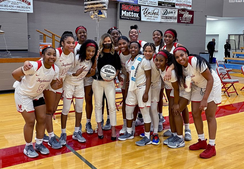 Moberly Area Community College women's head coach Hana Haden holds a commemorative basketball while being surrounded by her 2021 Lady Greyhounds players and celebrating her 100th career victory following Moberly's 101-38 home triumph March 27 against State Fair CC of Sedalia.