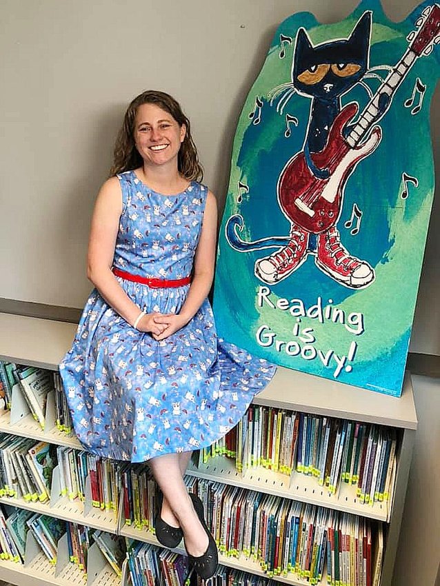 Katie Long, Little Dixie Regional Libraries Children's Librarian, sits on top of a shelf filled with children's reading material that she specialized in serving young readers the past three years. Long made a career move and finished her final day at the library on Sept. 10.