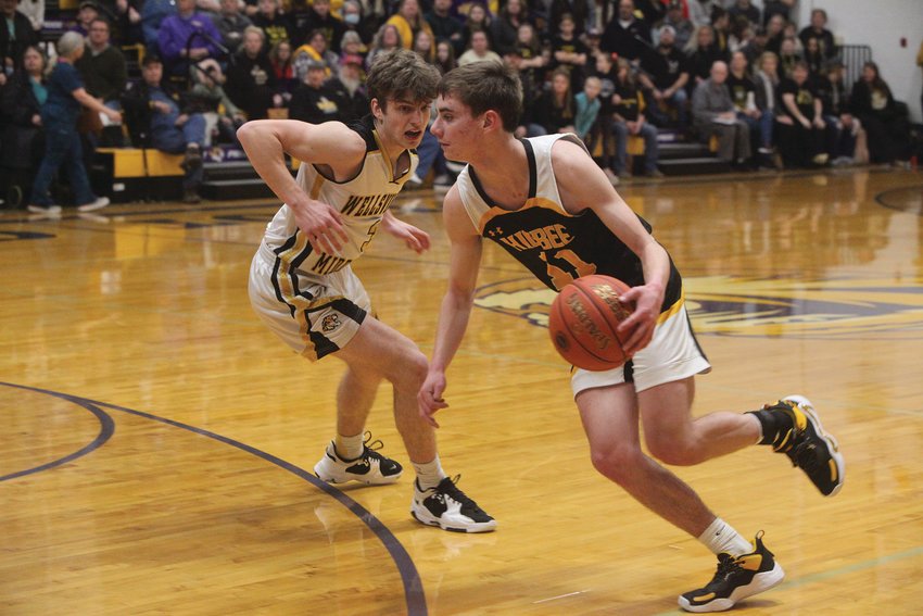 Higbee sophomore Derek Rockett tries to drive past Wellsville-Middletown&rsquo;s Jacob Mandrell in the second quarter of the Class 1, District 10 championship game on Feb. 25 at Pilot Grove High School. Rockett and the Tigers lost 38-34 to Wellsville-Middletown to finish their season at 26-3. (Theo Tate photo)