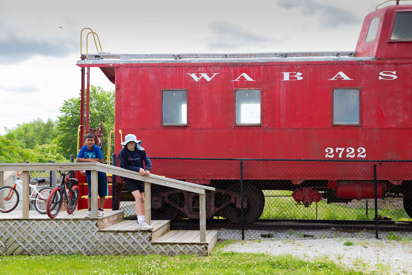 Jimmy Butler, of Kansas City, and Bartholomew James King pose by the Wasbash caboose in Depot Park in Moberly Wednesday. The cousins rode their bikes on the streets that, next week, will be filled with vendors, entertainers and a carnival during Moberly Rotary Club&rsquo;s annual Railroad Days festival in Depot Park.