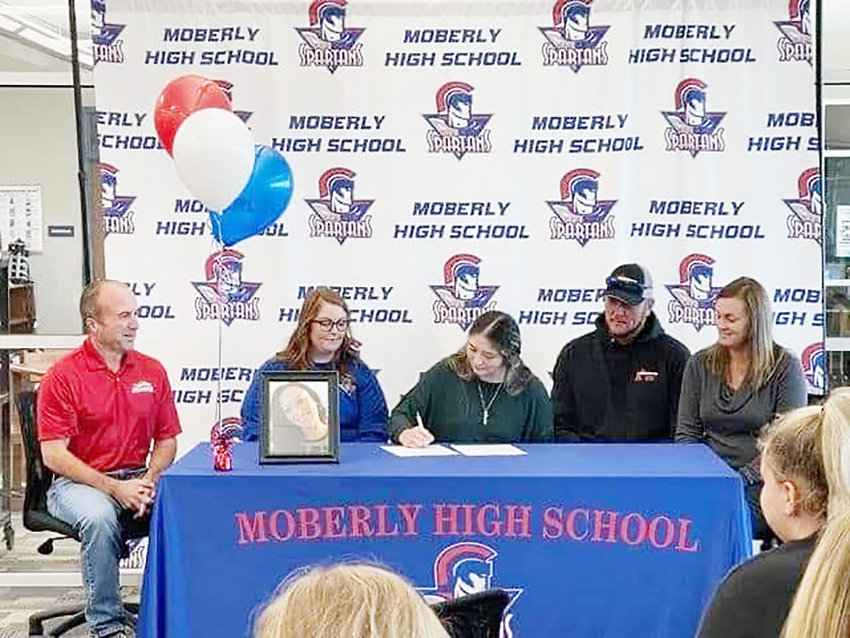 Madyson Klostermann (center) signs with Moberly Area Community College last fall while (from left) Greyhound head coach Matt Bauer, then Moberly High School assistant coach Angela Lee, Kevin Klostermann (Madyson&rsquo;s dad) and Ruchelle Jacobi (stepmom) look on. Klostermann was an all-district and all-conference player at Moberly, and will most likely pitch for the Greyhounds.