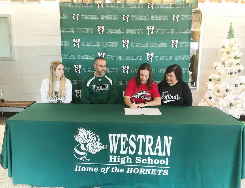 Westran High School assistant softball coach Jordan Harlan and Maddy Harvey's parents, Mark and Blaire Harvey, watch as Maddy puts pen to paper during last year &mdash; signing with Moberly Area Community College to continue her softball career.