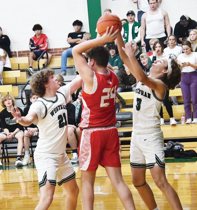 Westran High School boys' basketball players Ashden Dale (left) and Cooper Harvey (right) surround Novinger's Gage Brownell during Friday's season-opening game in Huntsville. The Hornets coasted to a 69-38 victory.