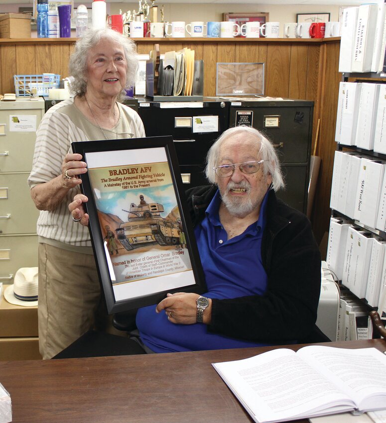 author/illustrator Larry Waterfield presents Joyce Campbell of the Randolph County Historical Society, a framed copy of his illustration of the Bradley Armored Fighting Vehicle. Similar illustrations comprise his book &ldquo;Show Me Missouri and Missourians.&rdquo; Waterfield, a native of Moberly, was at the Historical Society Saturday for a book signing and to discuss history with patrons. Photo by Joe Barnes