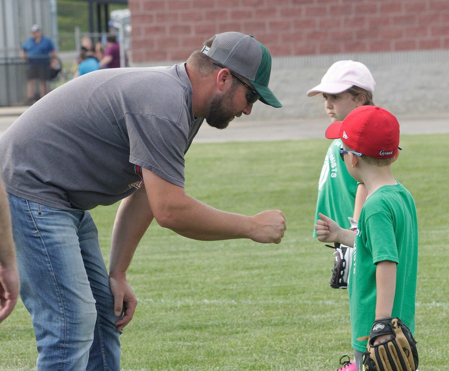 Huntsville Hawks assistant coach Brett White looks to receive a fist bump from his son Knox as the Hawks' T-ball team takes to the field to play a game.
