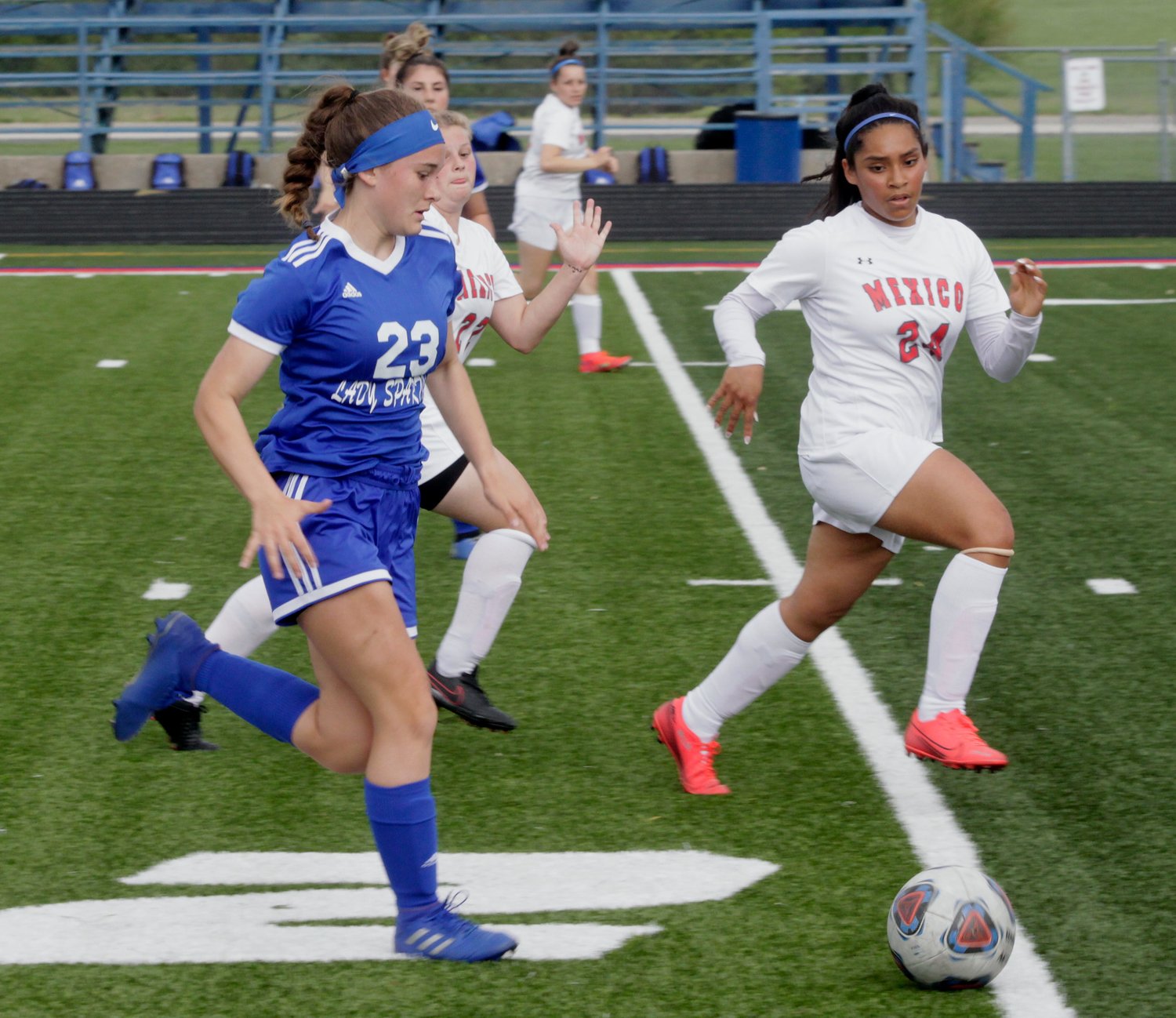 Moberly freshman Addie Holloway (#23) toes the soccer ball up the field Monday at Dr. Larry K. Noel Spartan Stadium while Mexico's Estrella Lopez (#24) runs alongside her. The Lady Spartans lost its home conference game 1-0 to Mexico.