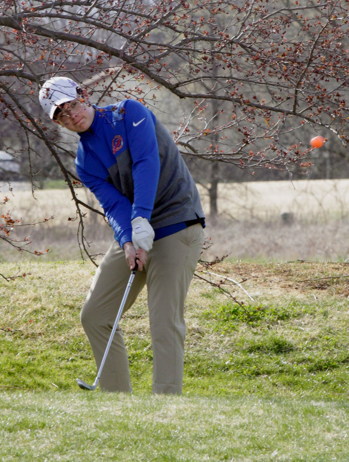 Moberly High School freshman Chase Nelson stands between tree limbs as he places his chip shot toward the green on hole no. 13 Tuesday at Heritage Hills Golf Course. Nelson turned in a score of 62 while playing the back nine holes, and the Spartans team lost its home dual to Boonville 234-245.