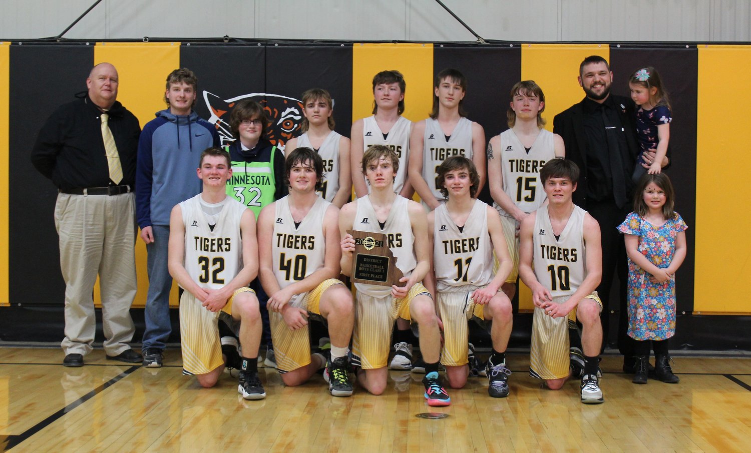 The 2020-21 Higbee High School boys basketball team won the Class 1 District 10 tournament championship, the school's first of its kind in athletic history, by defeating Community R-VI of Laddonia Thursday by a 61-31 result at home. Team members are (wearing white jerseys, left to right) Jordan Fuemmeler, Jamie Smith, Keetun Redifer, Derek Rockett and Luke Ritter. Second row players are Chevy Grimsley, Will Spilman, Jaxon Hudson and Chad Crawford. Head coach Tanner Burton is shown second row right holding his daughter, and assistant coach David Roush (second row, left).