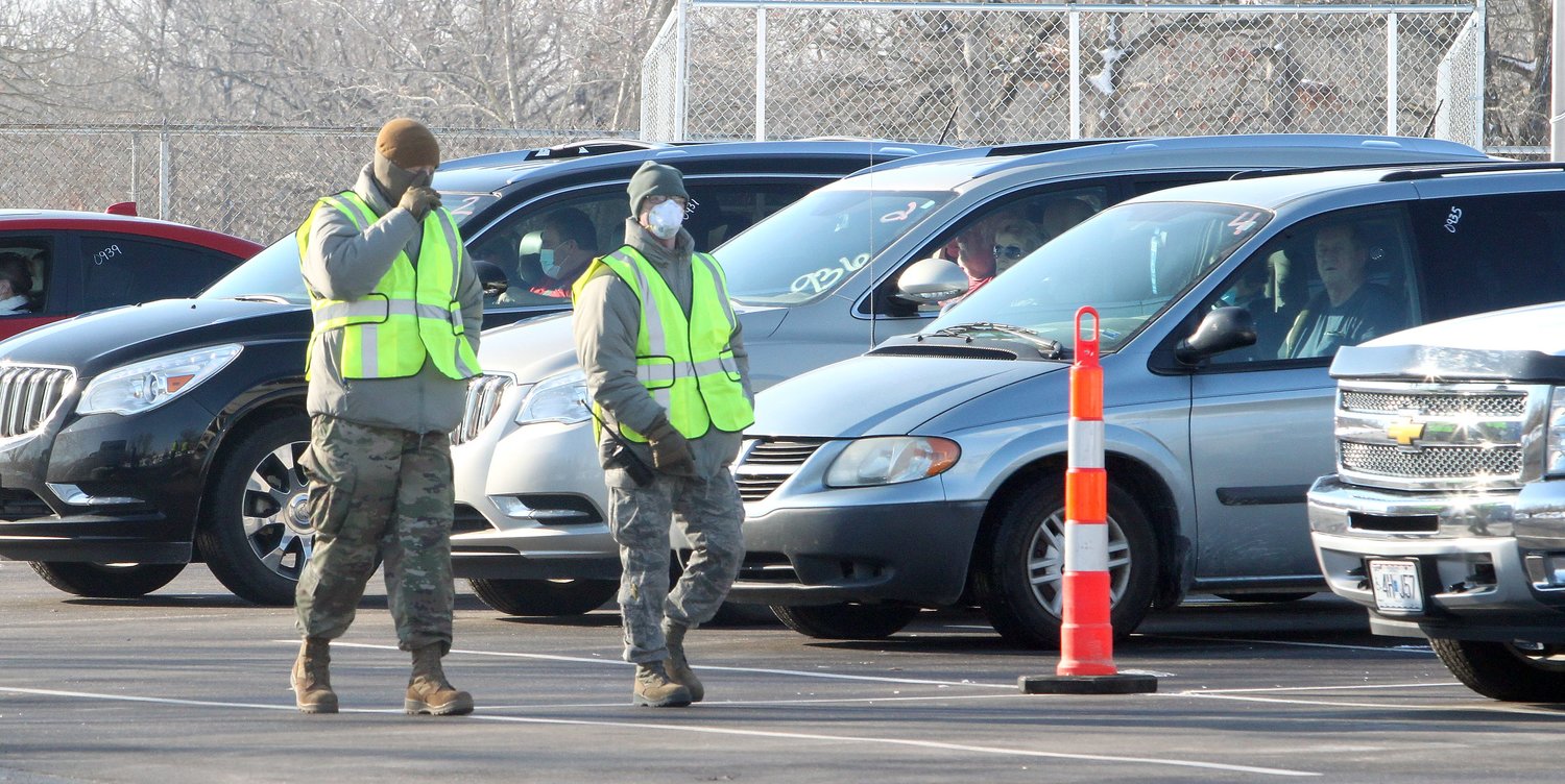 Members of the Missouri National Guard's 139th Airlift Wing Division at St. Joseph walk in front of vehicles as they check on the well-being of motorists about 15 minutes after they received a COVID-19 vaccine on Jan. 28.