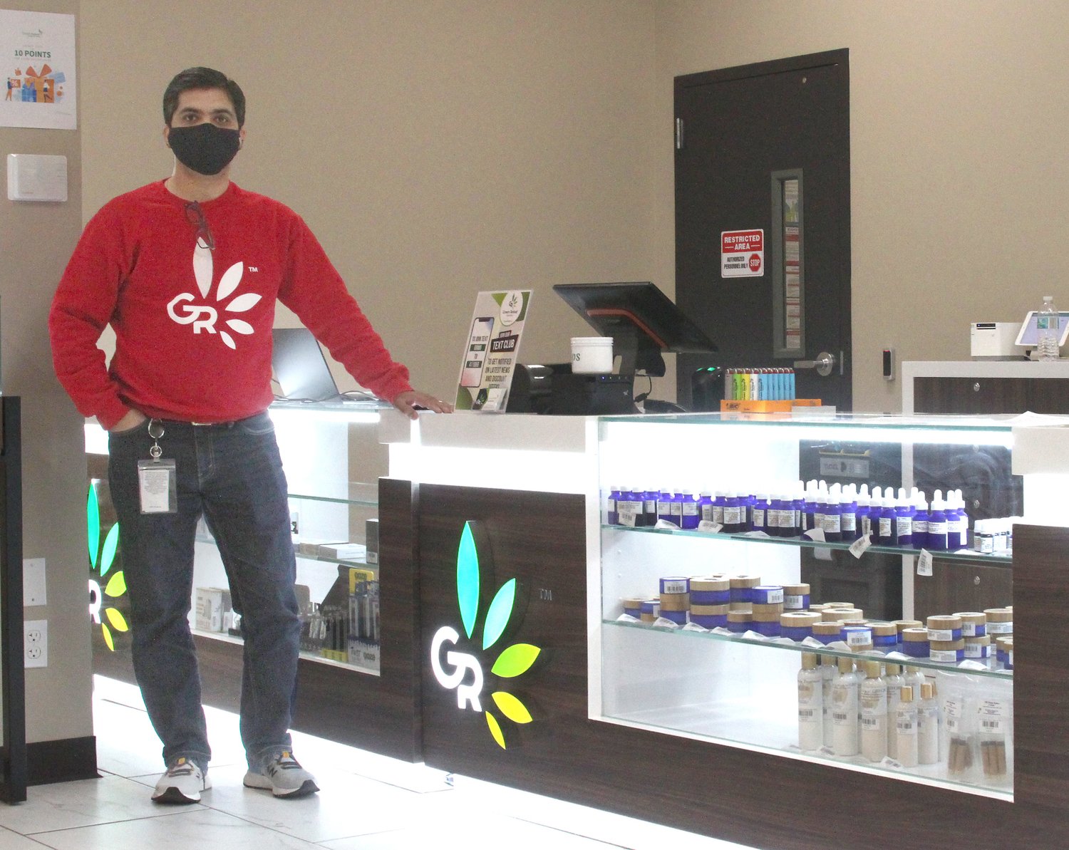 Jay Patel, owner of Green Releaf store in Moberly, stands next to a retail counter display showing a variety of medical marijuana/cannabis products offered for state-approved patients.