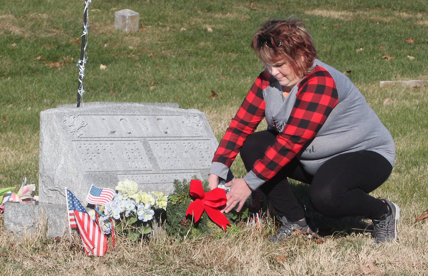 Kim Eagan places a wreath Saturday on her father's grave, Herbert Joe Long, who served in the U.S. Armed Forces with the merchant marines in World War II and air force during the Korean War. Moberly Altrusa Club held its 3rd Annual Wreaths of Honor event Nov. 28 at Oakland Cemetery.