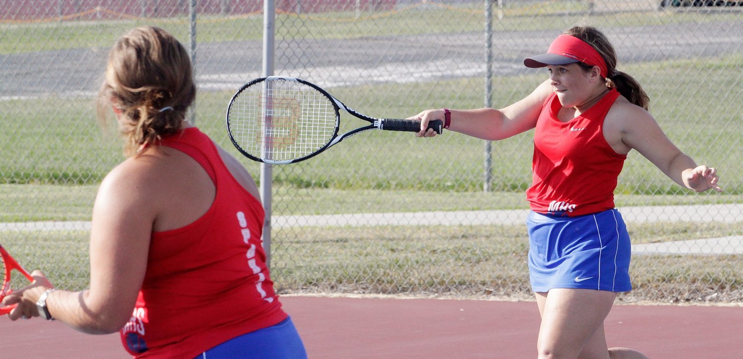 Rachel Morgan of Moberly High School  reaches forward to make a return volley while her No.  3 tennis doubles partner Sam Carl observes Wednesday, Sept. 1 during a home dual meet against Marshall. The Lady Spartans team lost a close 5-4 decision to their North Central Missouri Conference rival.