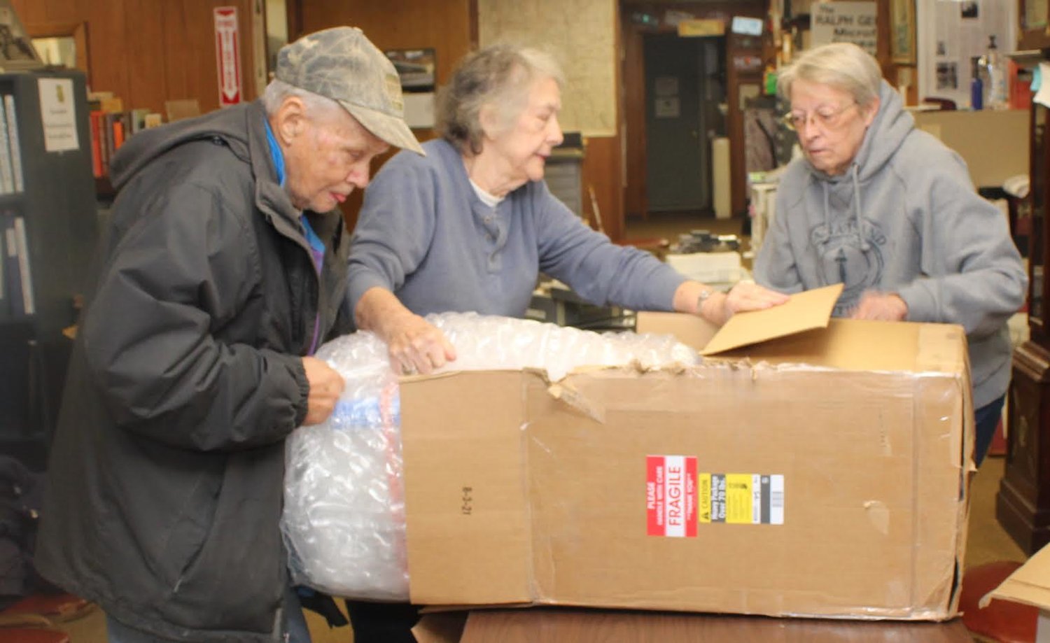 David Campbell, Joyce A. Cooper-Campbell and Shirley Slusing carefully unpack the 70-pound bust of local favorite son Omar N. Bradley recently donated to the Randolph CountyHistorical Society by the Chosin Few, Korean War veterans who survived the Battle of Chosin Reservoir in 1950. Members of the Moberly Spartans football team had to carry the package into the museum. (Joe Barnes)