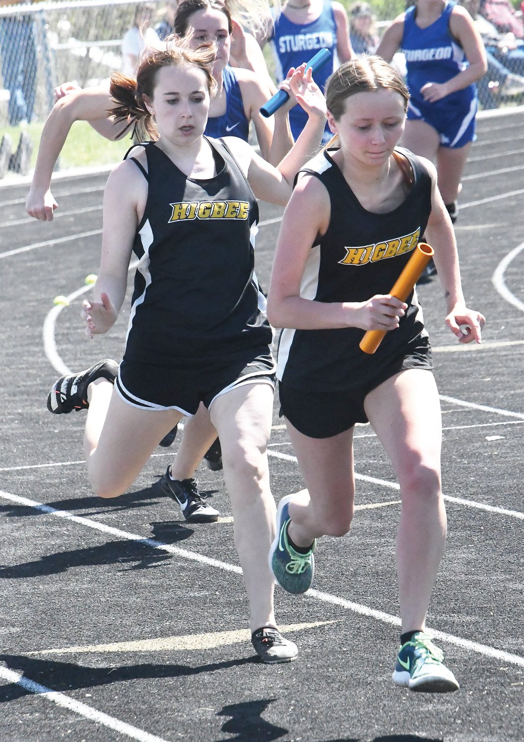 Higbee’s Joey Westfall (left) hands the baton to Madison Eames in the 4x100-meter dash as the Tigers finished second overall and advanced to the sectional meet.
