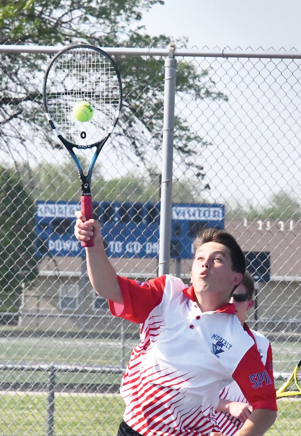 Moberly High School’s Ryan O’Loughlin delivers a smash during a doubles match versus Father Tolton Regional Catholic at the Class 1 District 7 championship Wednesday.