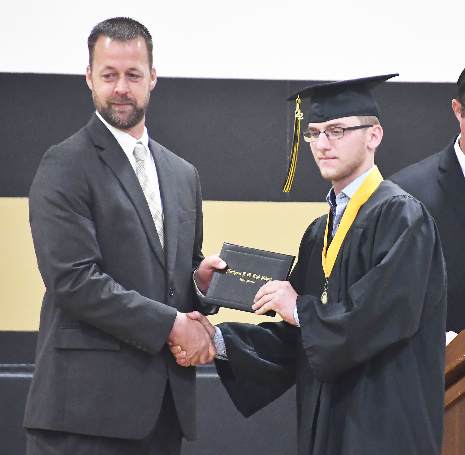 Cairo board of education president Henry Westhues presents a diploma to Class of 2022 graduate Brandon Schumann.