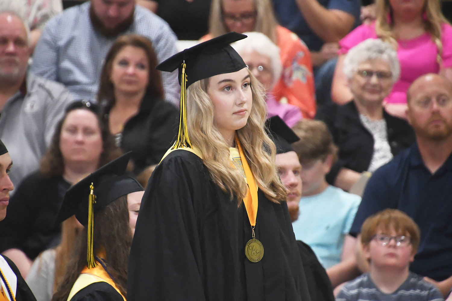 Class of 2022 graduate Carly Hunsaker stands and listens as her scholarship information is read.