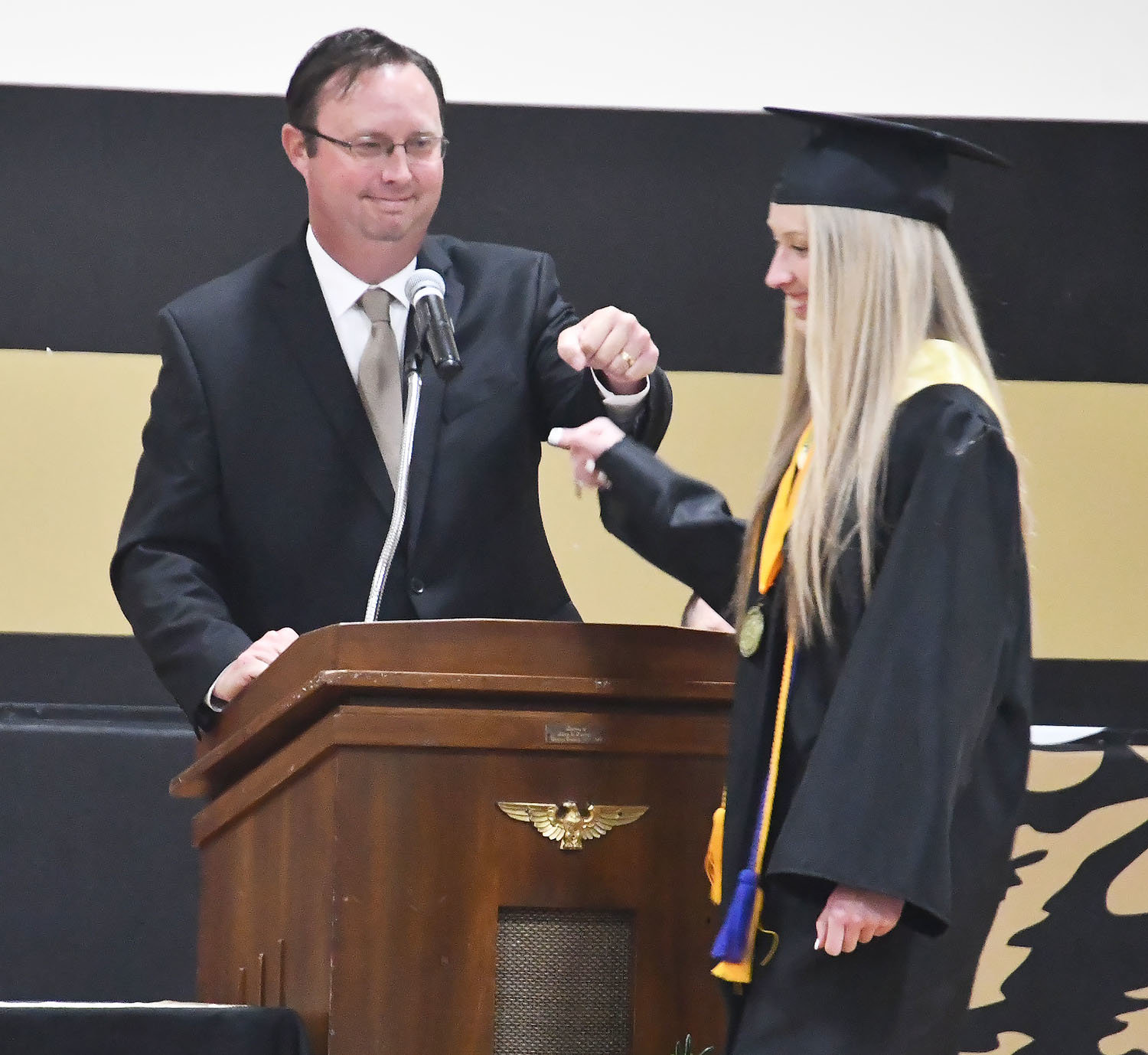 Cairo High School principal Greg Taylor gives a fist bump to his daughter, Morgan, just before Morgan received her diploma on Sunday.