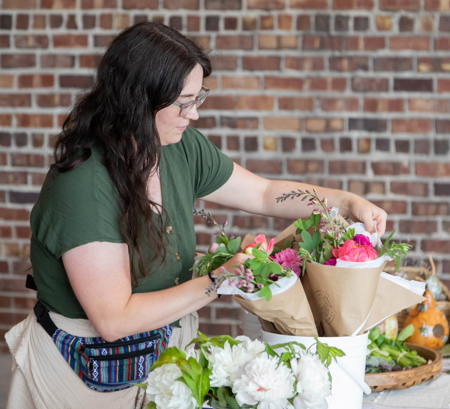 Kadie Crivello arranges flowers during the inaugural farmer’s market of the 2022 season. Despite some rain, residents arrived to check out the vendors and activities offered Thursday at The Fennel.