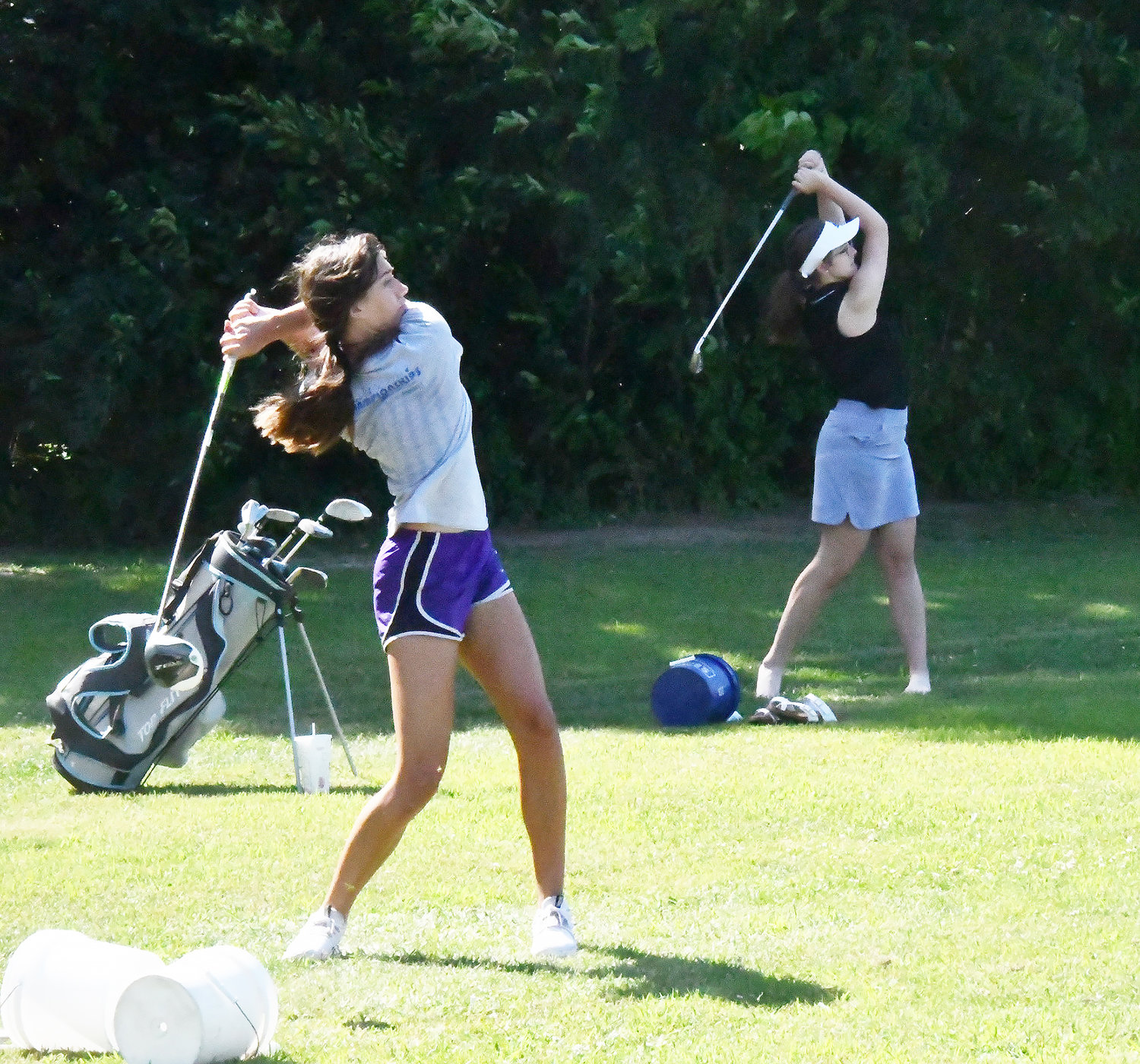 Cairo girls' golfers Journey Sander (left) and Addison Pollard follow through on their shots.