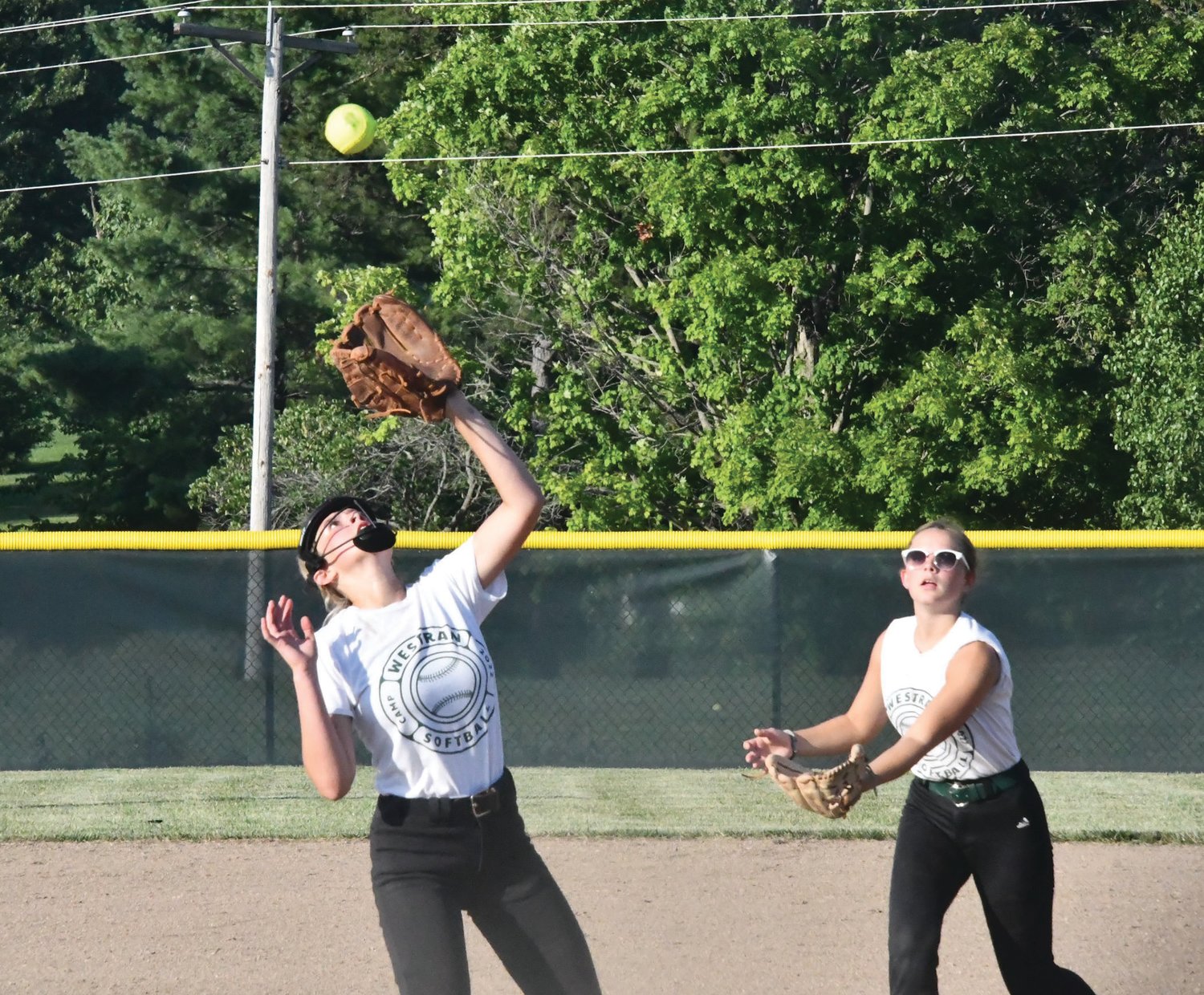 Westran High School pitcher Kyleigh Carroll (left) prepares to catch the ball while teammate Kiyah Massey looks on.