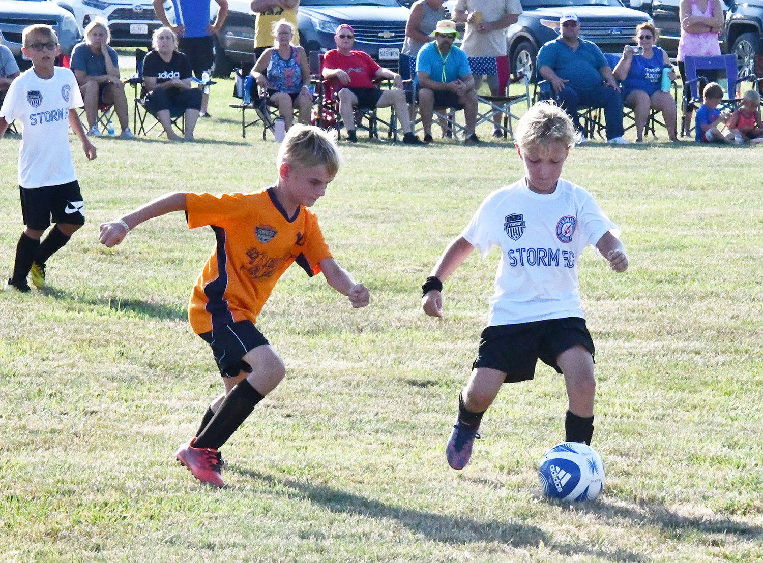 Storm 10-under soccer player Christian Doubrava tries to play keep away while teammate Seth Swartz looks on in the background.