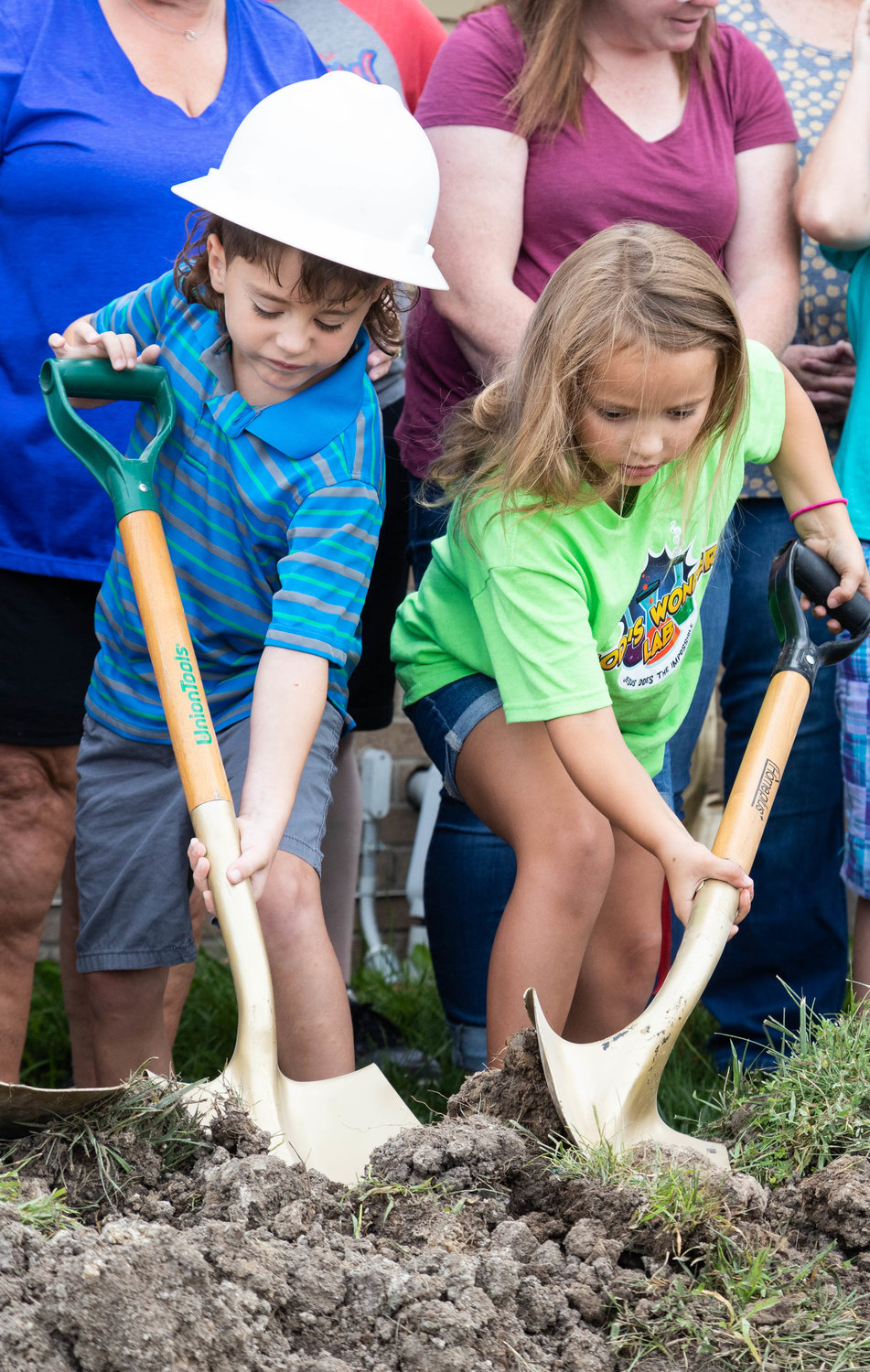 Chase Soendker and Ryann Smith struggle with uncooperative clods of dirt at the groundbreaking for a new addition to Moberly’s Early Childhood Learning Center.