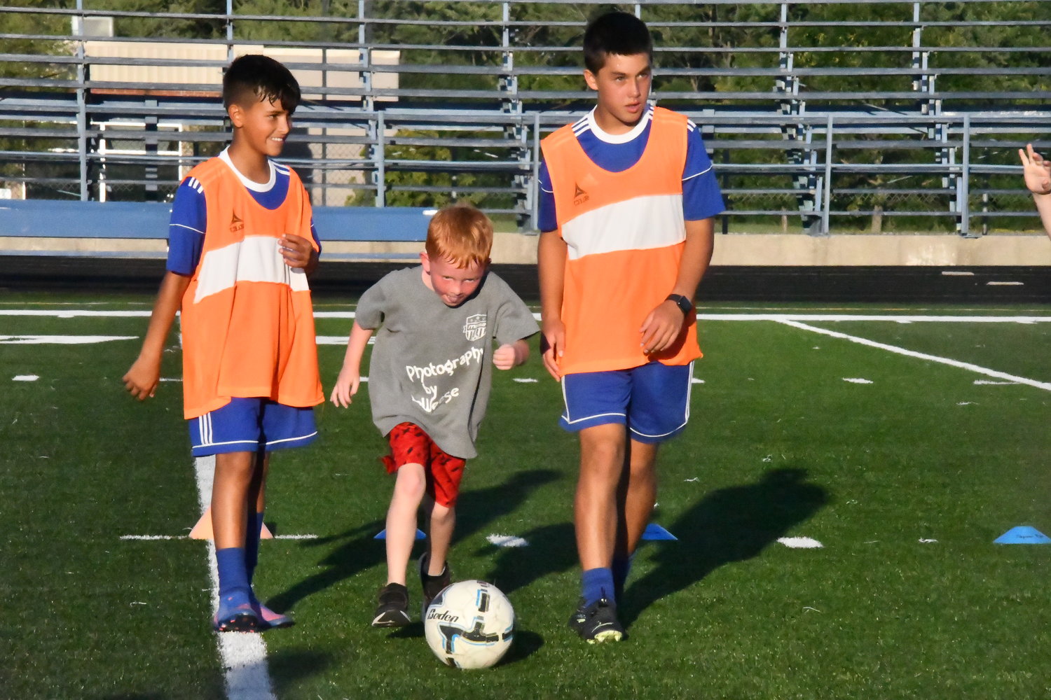 Caden Lucas, 6, dribbles a ball during the 3-on-3 soccer event, helped by two Moberly High School players.