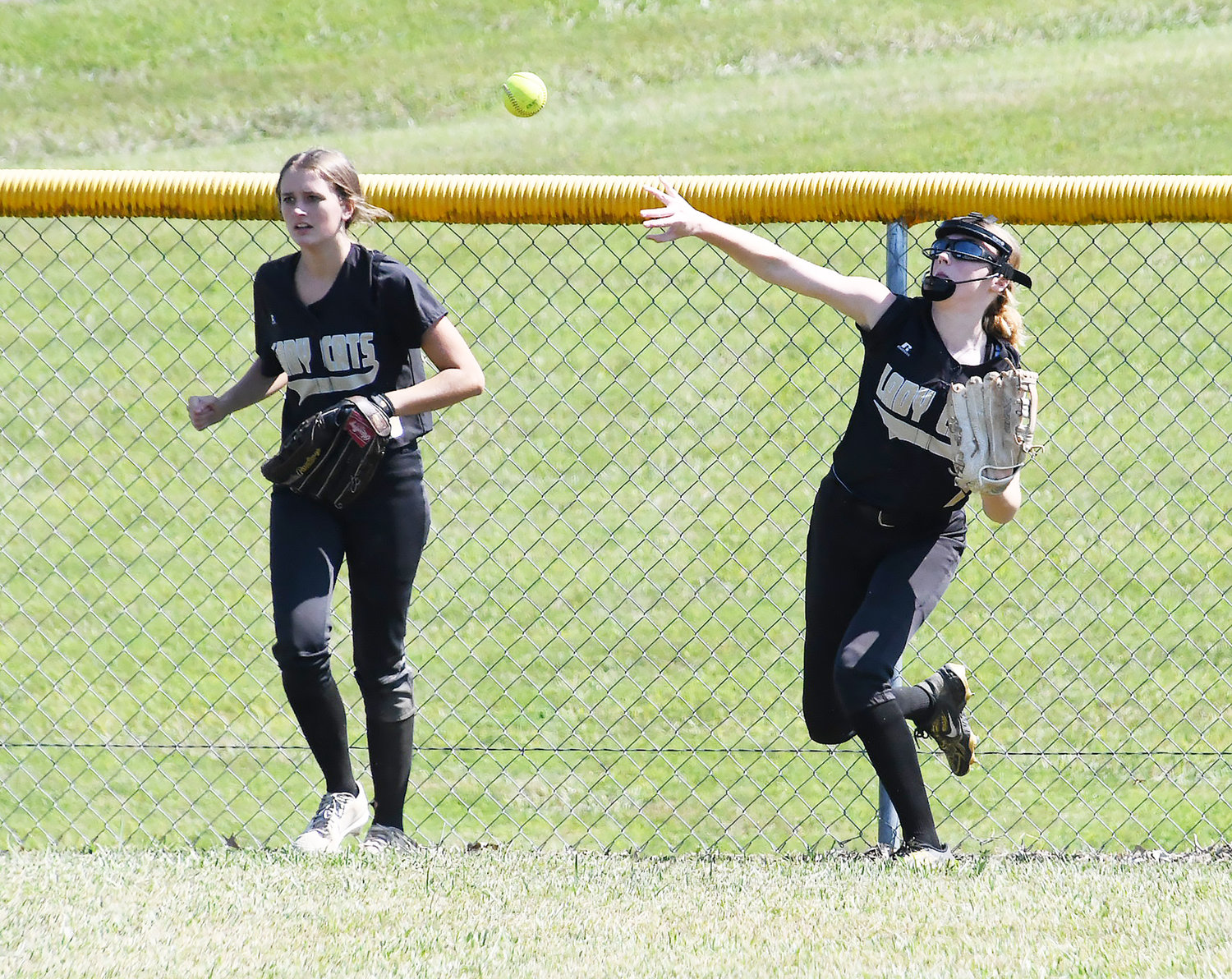 Cairo's Abi Ogle (right) throws the ball back toward the infield after a Macon triple. Jersey Bailey also is photographed, at left.