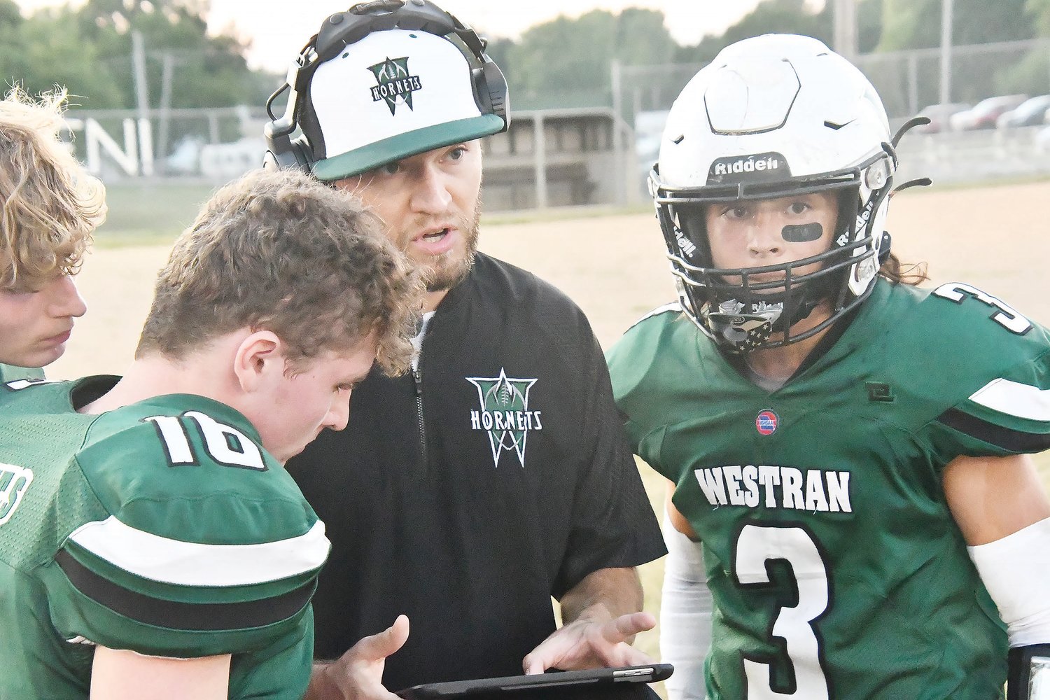 Westran assistant football coach Andrew Baxley talks with players Brennon Long (16) and Korbin Perry (3) during a timeout Friday.