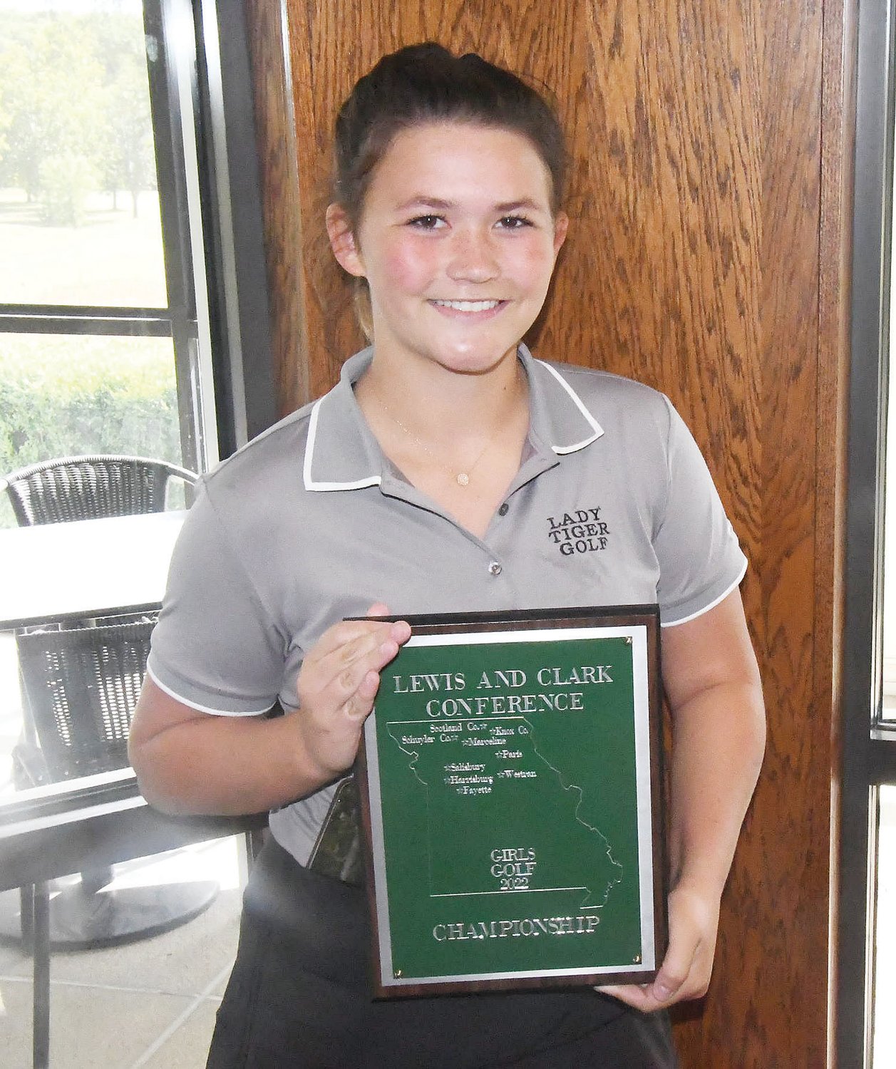 Tess Sheerman smiles and proudly displays Marceline's first-place plaque as the Tigers won the Lewis & Clark Conference title on Tuesday at Heritage Hills Golf Course in Moberly. Sheerman also was the medalist with an 87.