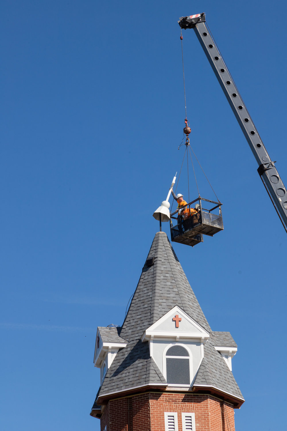 Workmen place a cross over the top of the lightning rod on Coates Street Presbyterian Church in Moberly.
