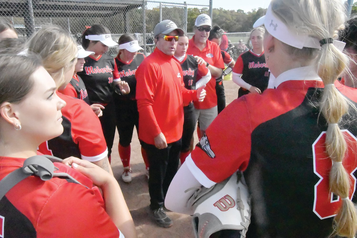 Moberly Area Community College head softball coach Matt Bauer talks with the Greyhounds after winning Game One.