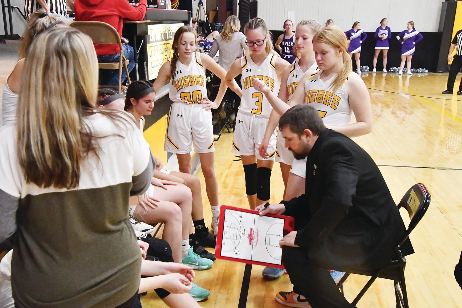 Coach Tanner Burton talks with the Higbee girls' basketball team during a timeout in Tuesday's game against Bevier.