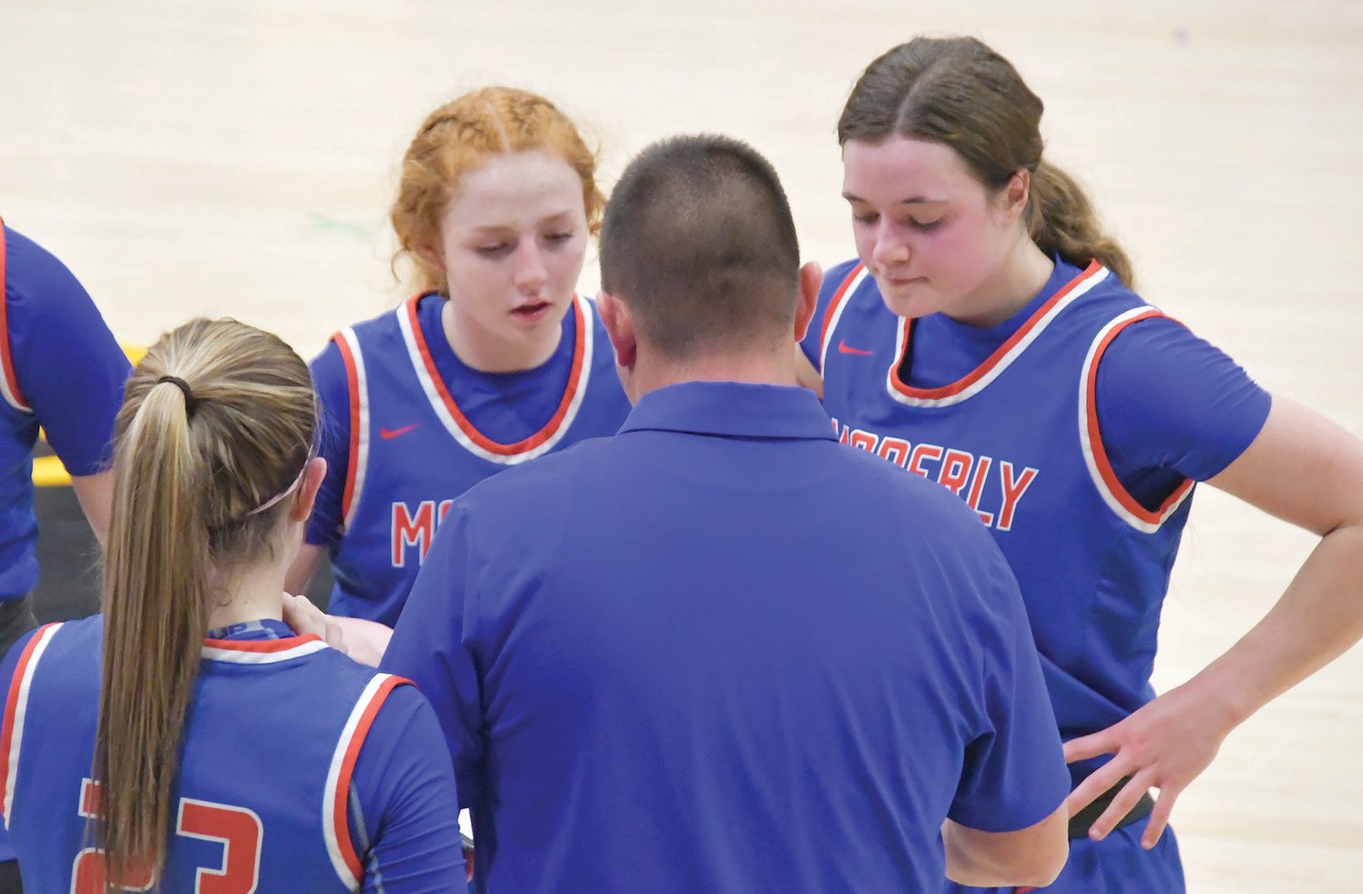 Moberly's Haley Baker (left) and Grace Billington listen to head coach Tony Vestal during a timeout in Monday's game. The Spartans defeated the Panthers, 58-29.