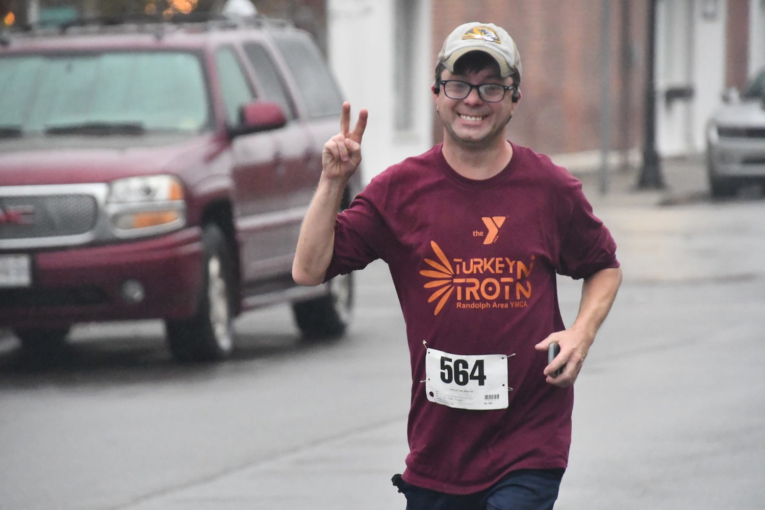 Danny Owens smiles and gives the "peace" sign as he runs toward the finish line.