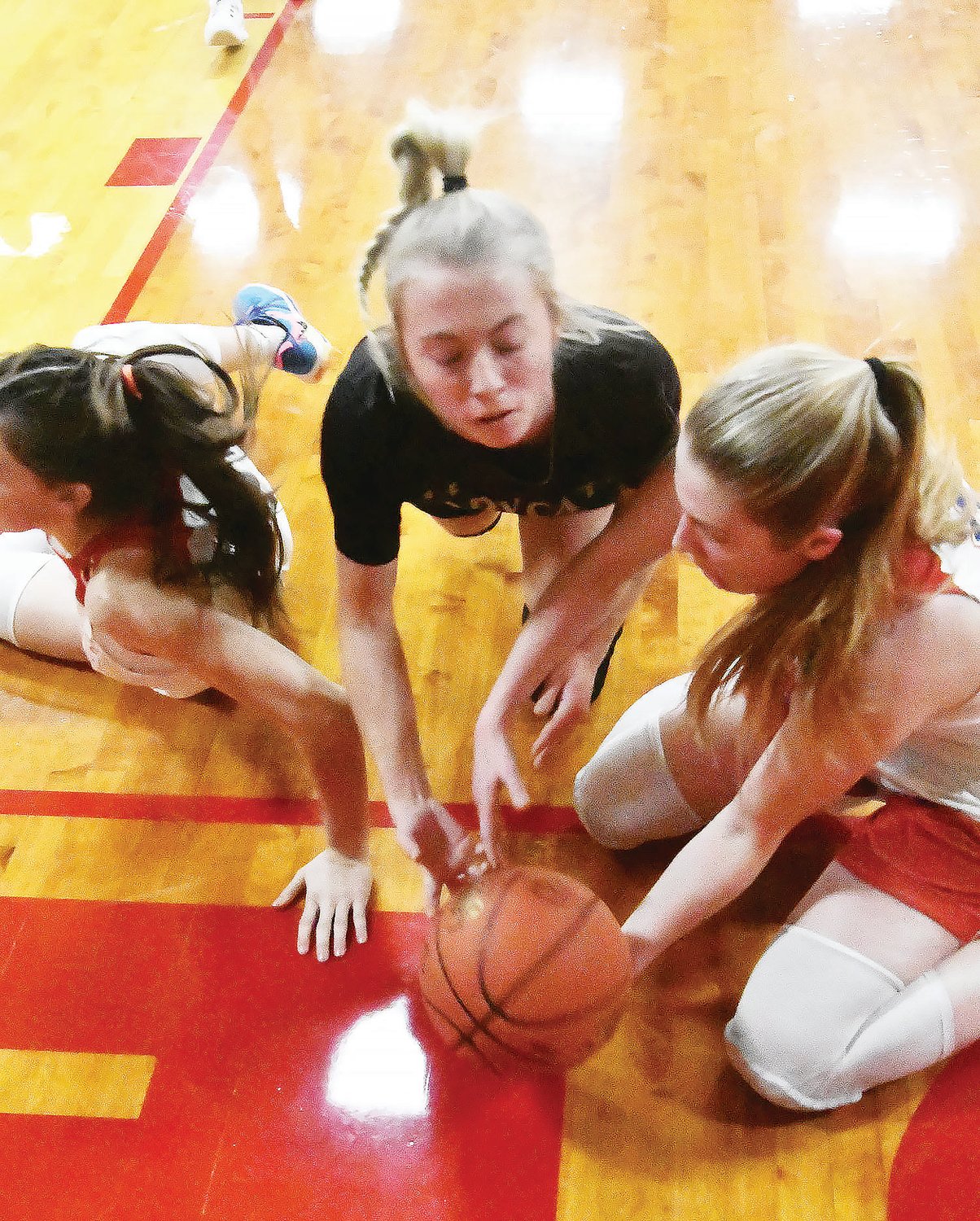 Avery Brumley vies for a loose ball with two players from South Shelby. The ball went out of bounds and was awarded to the Cardinals.