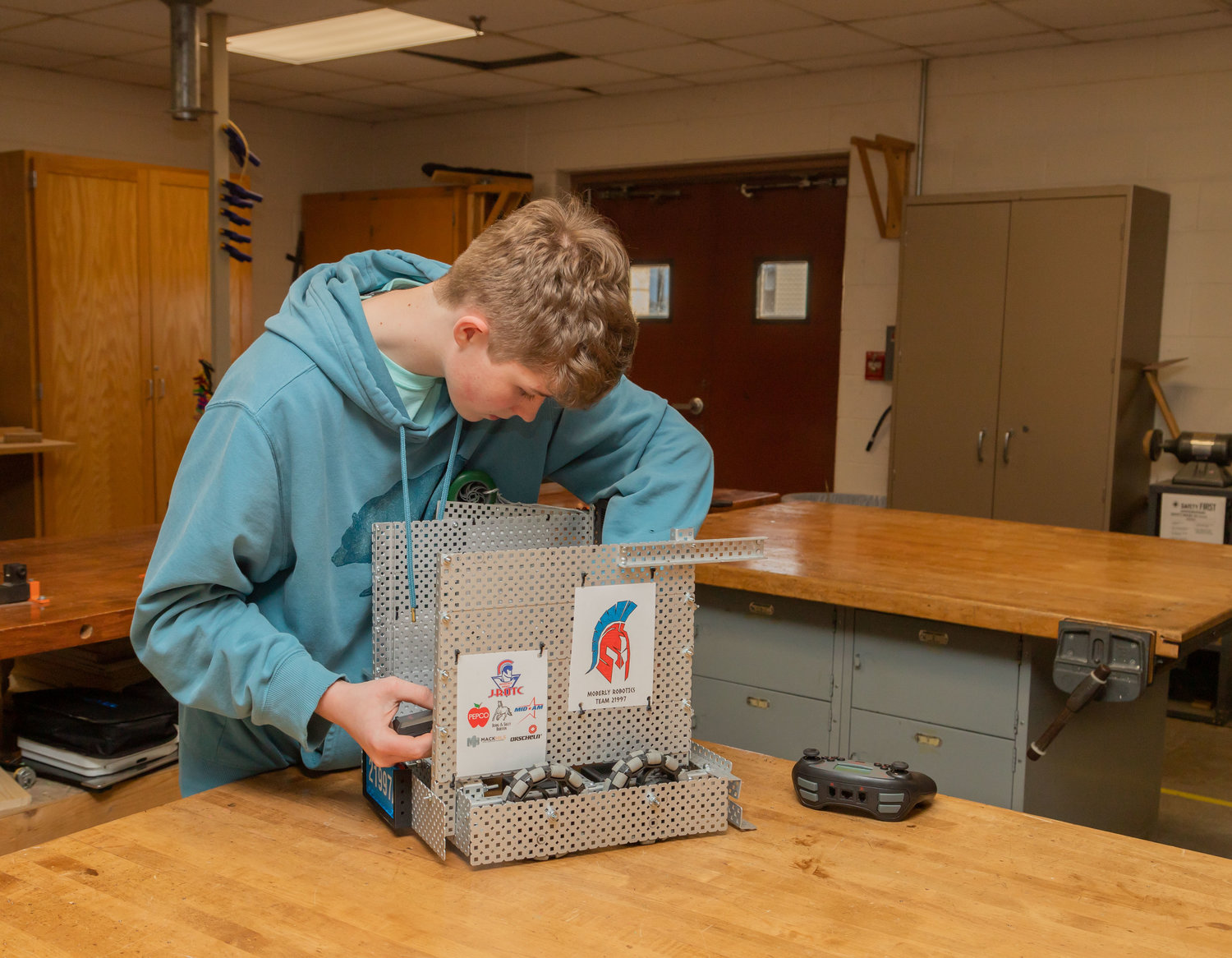 Marshall Dixson puts a battery in the Junior ROTC team robot, Slushie, last week in preparation for practice before the state competition in March.